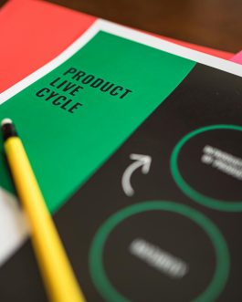 Close-up of a product life cycle diagram with colorful papers and a pencil.