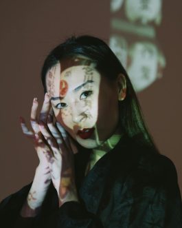 Creative portrait of a young woman with artistic text projections on her face.