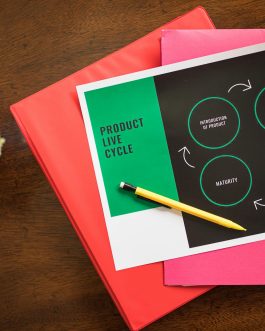 Flat lay of a product lifecycle illustration with a pencil and folders, ideal for business presentations.