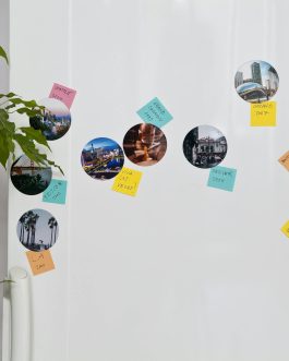Fridge door adorned with vibrant sticky notes and travel photos. Perfect for travel inspiration.